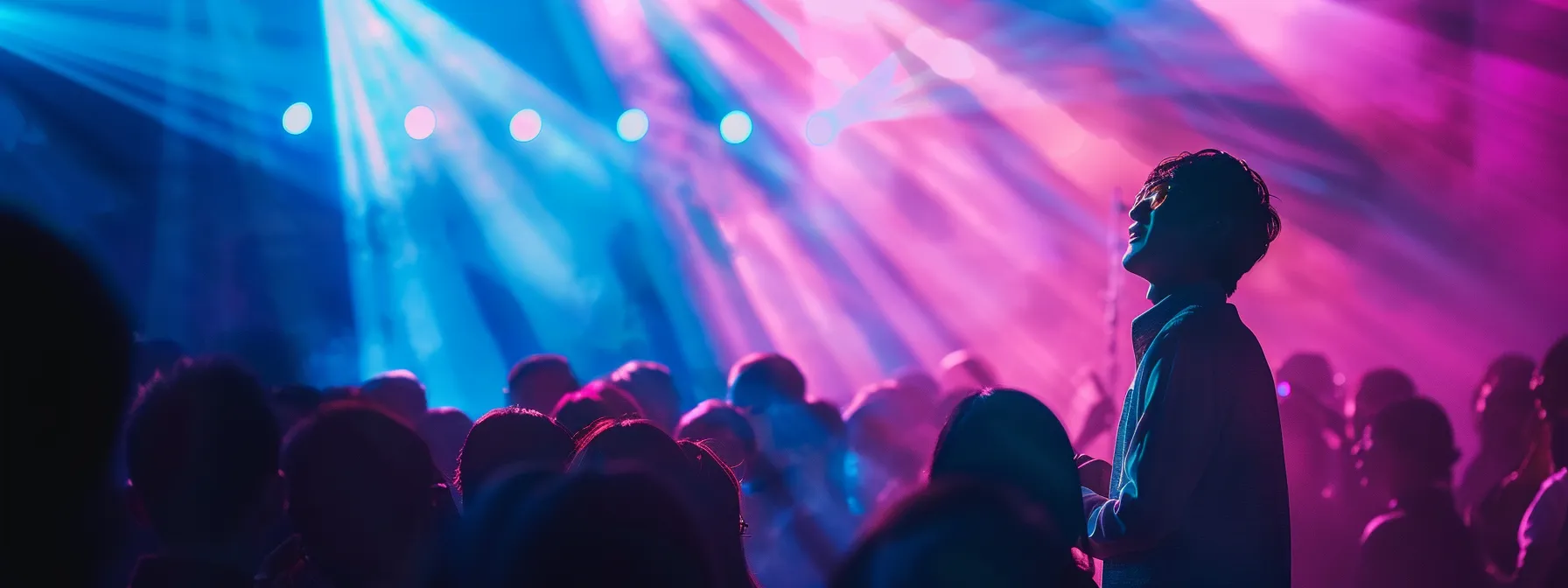 a focused artist passionately performing on stage, under vibrant colored lights, embodies the pursuit of music scholarships, surrounded by captivated audience members and an air of hopeful ambition.